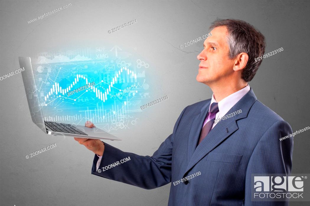 Imagen: Man holding laptop projecting financial information, diagrams and charts.