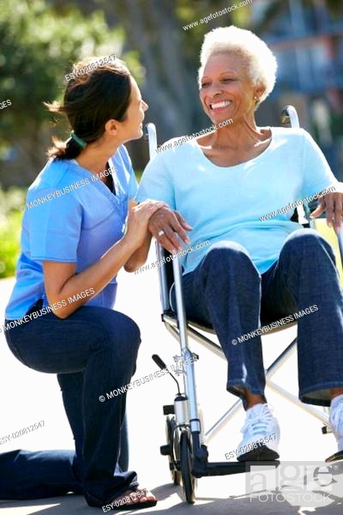 Stock Photo: Carer Pushing Senior Woman In Wheelchair.