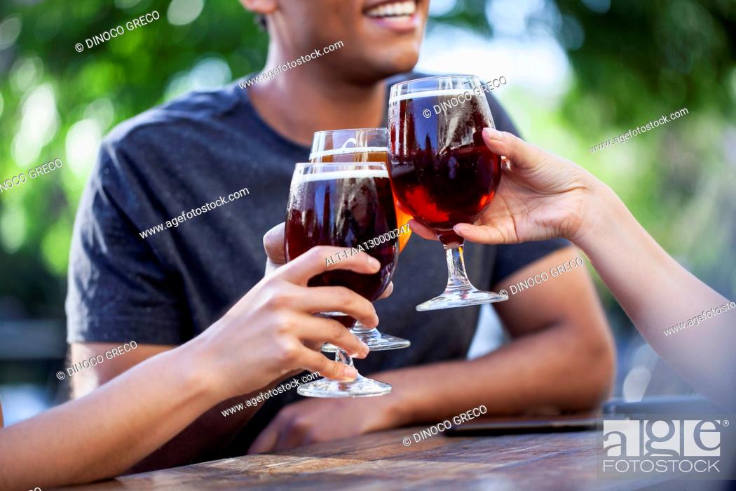 Photo de stock: Mid section view of three friends toasting with beers.