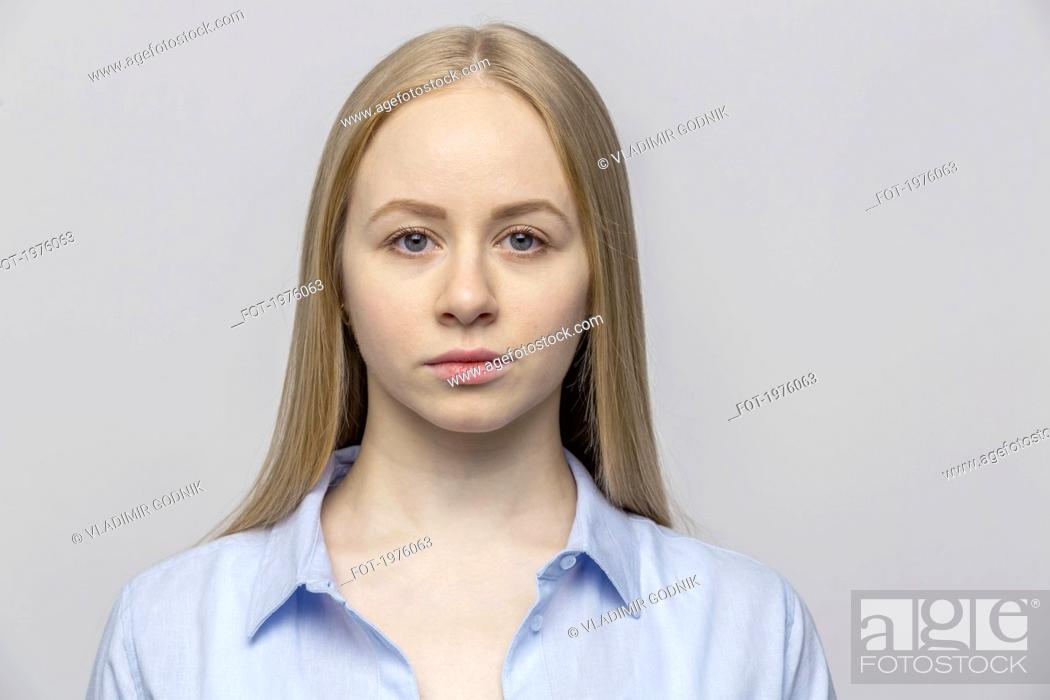 Stock Photo: Portrait serious young woman against gray background.