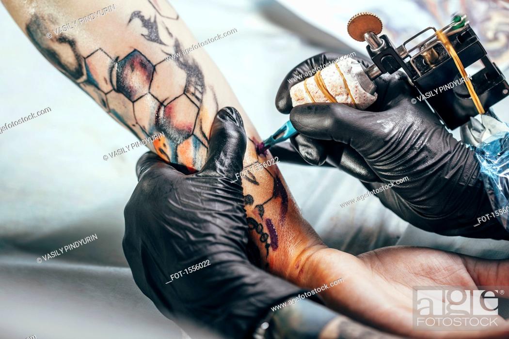 Artist wearing gloves tattooing design on human hand, Stock Photo, Picture And Royalty Free Image. Pic. FOT-1556022