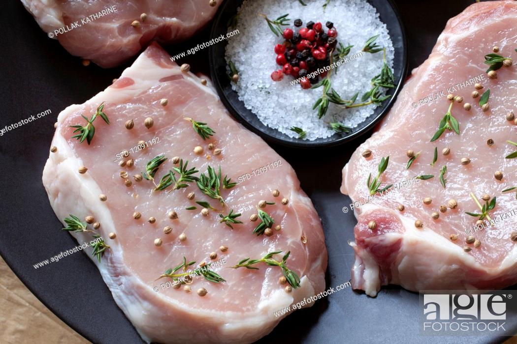 Stock Photo: Raw pork chops seasoned with thyme, coriander, salt and pepper.
