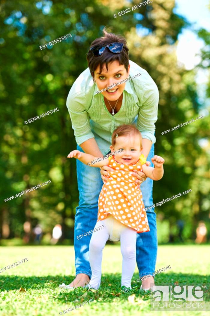 Stock Photo: happy mother and baby child in park making first steps . Walking and hugging.