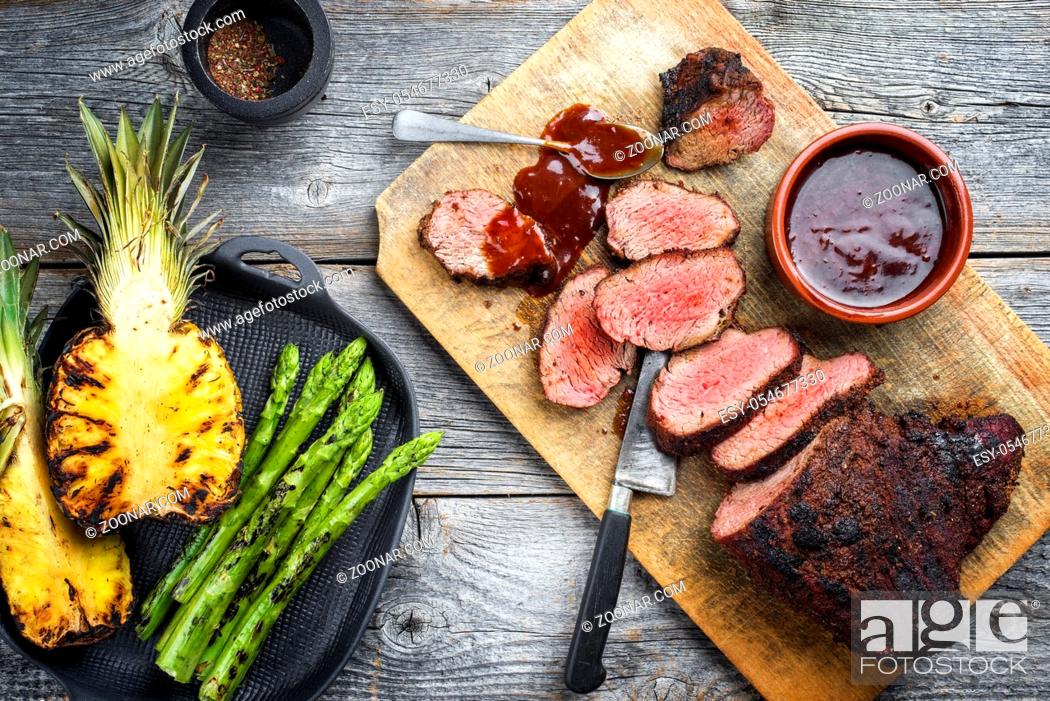 Stock Photo: Barbecue dry aged wagyu tri tip steak with grilled pineapples and green asparagus top view on a wooden cutting board.