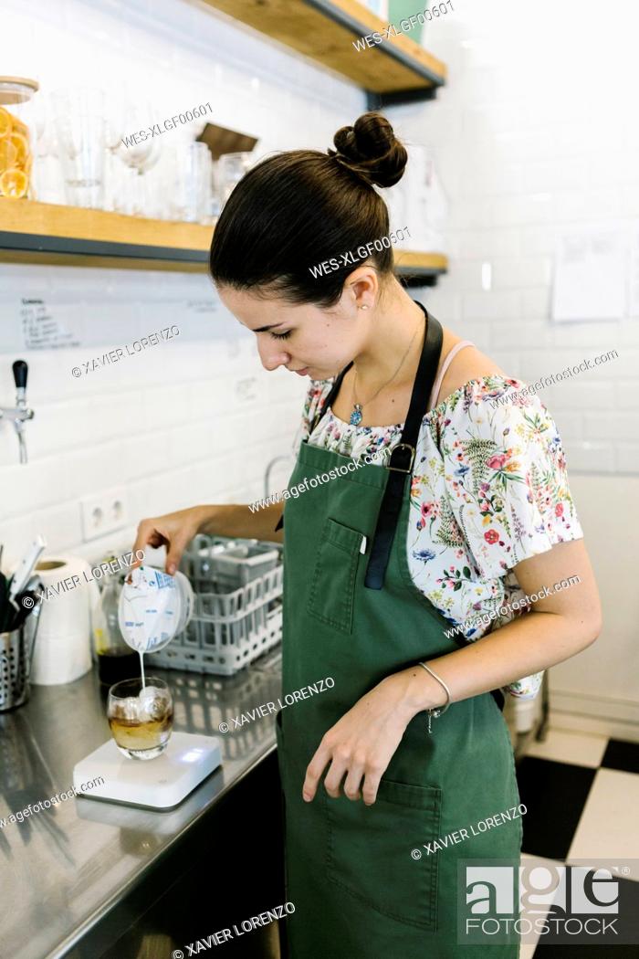 Stock Photo: Barista pouring milk in coffee while standing in kitchen at coffee shop.