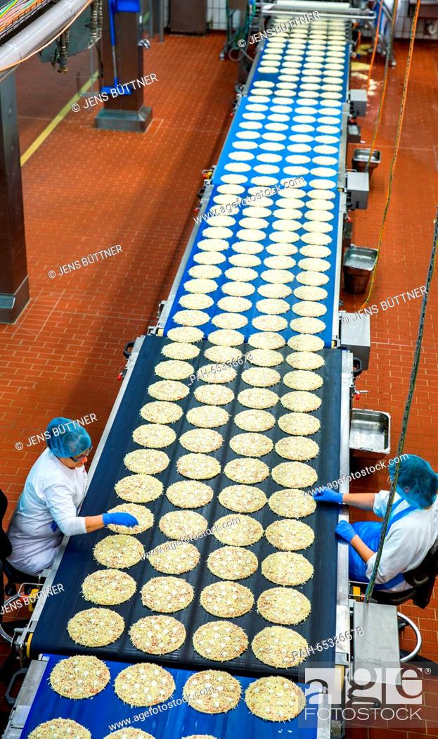 Stock Photo: Employees inspect the base used for frozen pizzas at a production line in the pizza plant of food manufacturer Dr. Oetker in Wittenburg, Germany.
