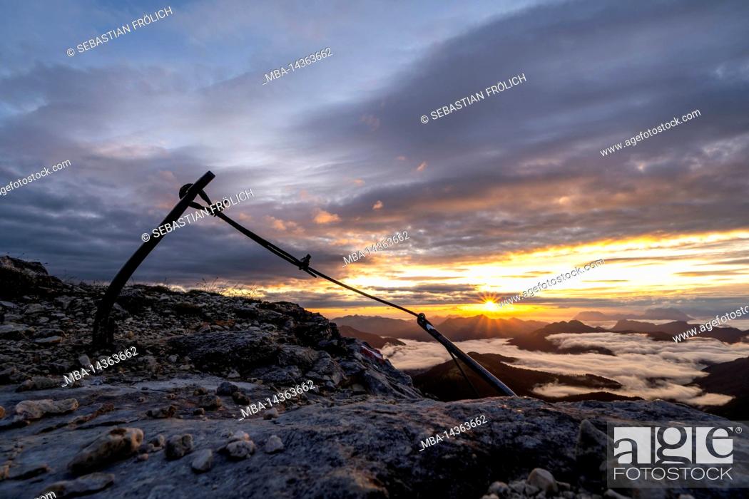 Stock Photo: Old wire rope belay on Guffert at sunrise over the Alps. In the background fog over the Rofan and the Brandenberg Alps, with colorful clouds.