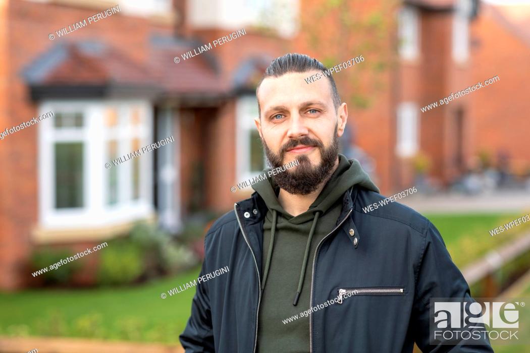 Stock Photo: Confident bearded man standing outside new home.