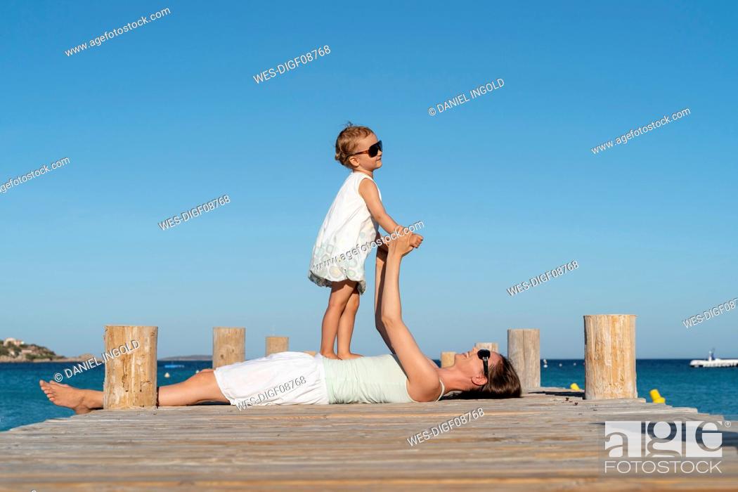 Stock Photo: Happy mother lying with daughter on a jetty at the sea.