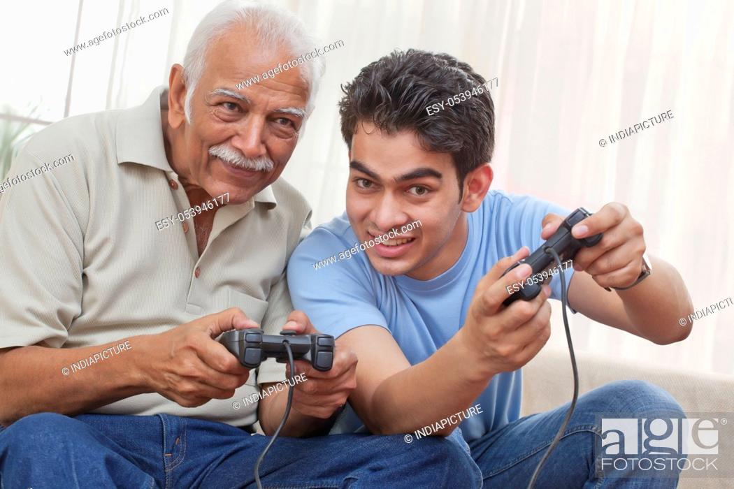 Stock Photo: Grandfather and grandson playing video game.