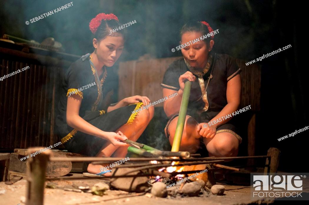 Stock Photo: Two women wearing traditional costumes are sitting at a campfire at the Mari Mari Cultural Village near Kota Kinabalu, Malaysia, on 27 October 2014.