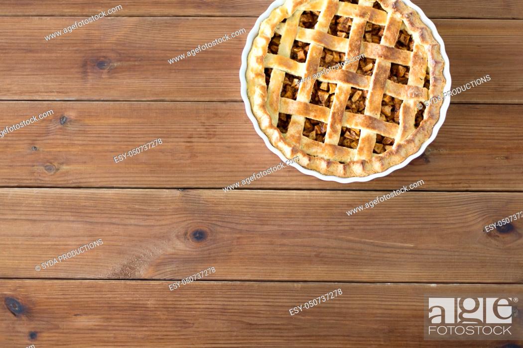 Stock Photo: close up of apple pie in mold on wooden table.