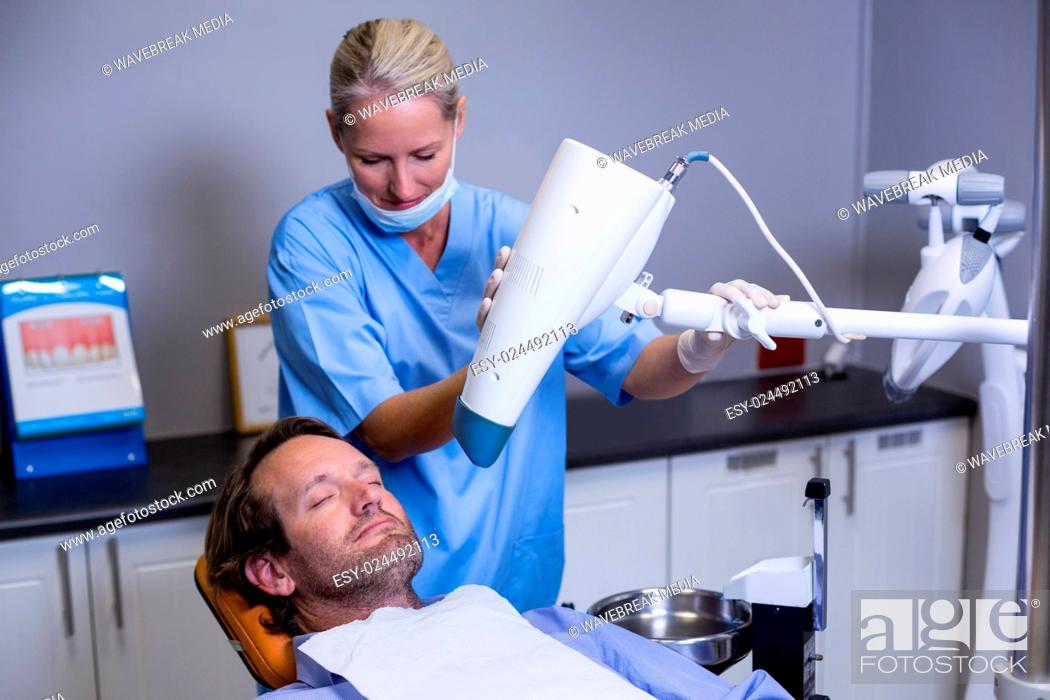Stock Photo: Dentist assistant adjusting light over patients mouth.