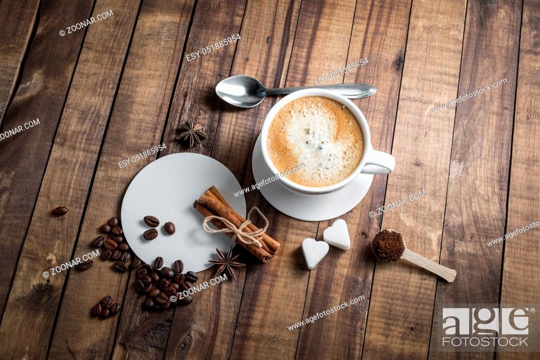 Stock Photo: Coffee and spices. Coffee cup, cinnamon sticks, coffee beans, anise, sugar, spoon and beer coasters on wood table background.