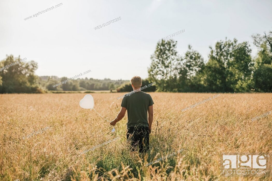 Stock Photo: Young man holding white heart shaped balloon.