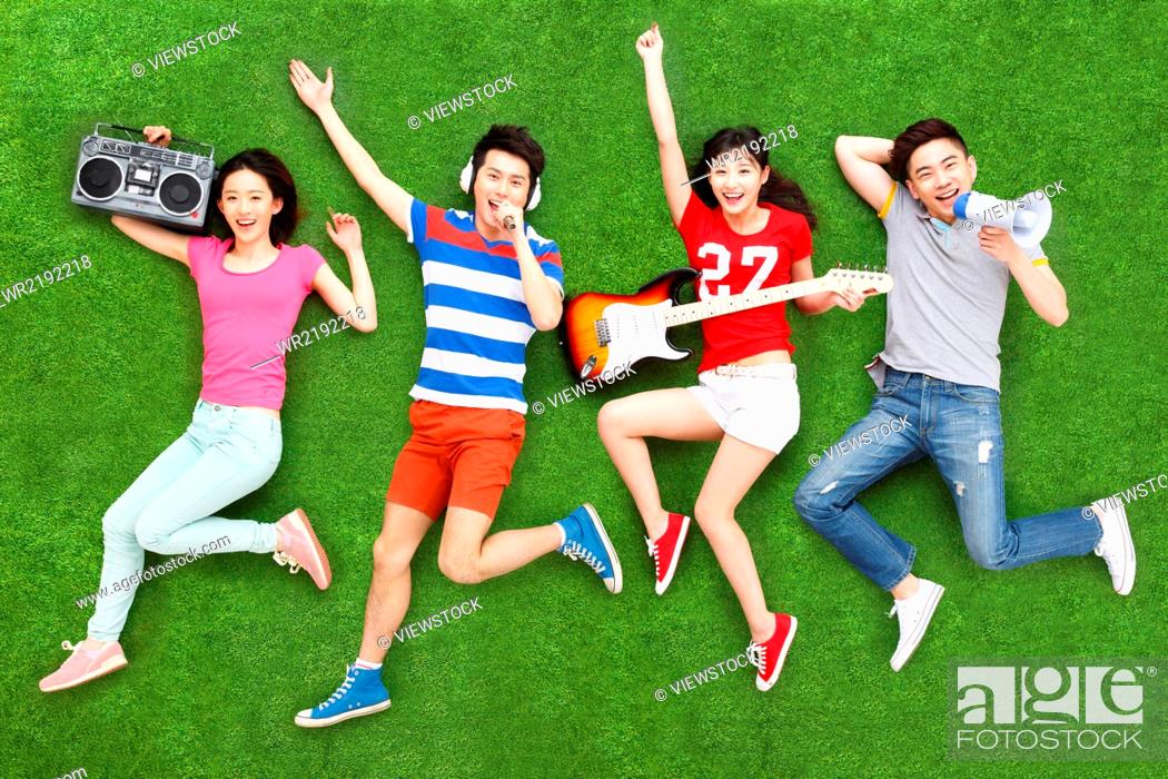 Stock Photo: Young people on grass playing guitar and singing.