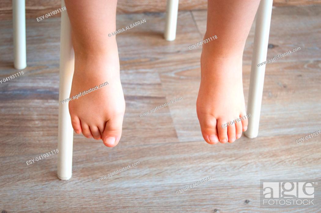 Imagen: Feet of a child sitting in a chair. Natural lighting.