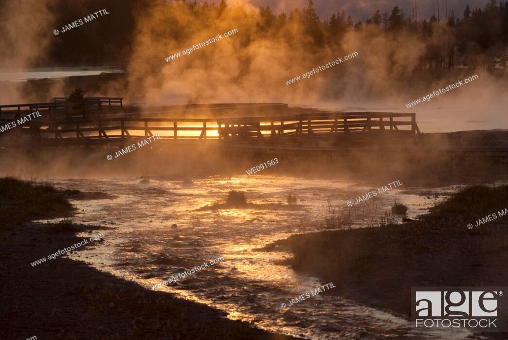 Stock Photo: The setting sun reflecting on Firehole Lake geothermal area and boardwalk suggests a boiling pool of magma below.