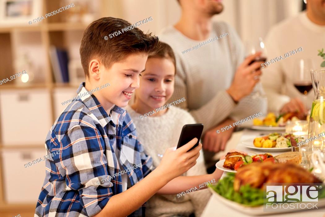 Stock Photo: boy with sister using smartphone at family dinner.