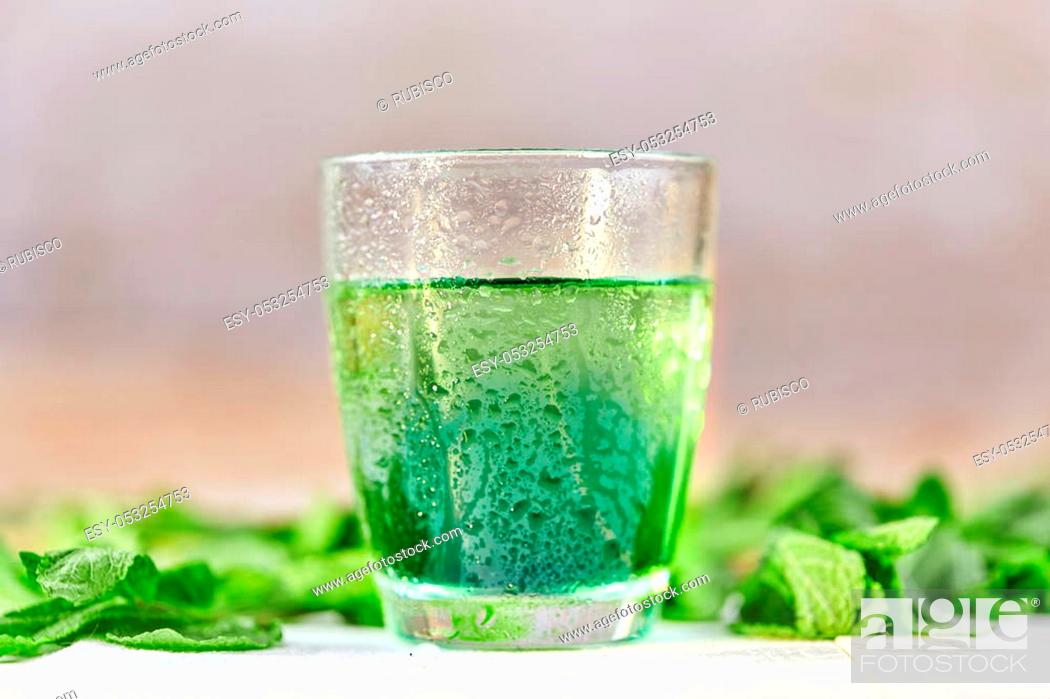 Stock Photo: Green mint chlorophyll drink in glass with water drops on white table.