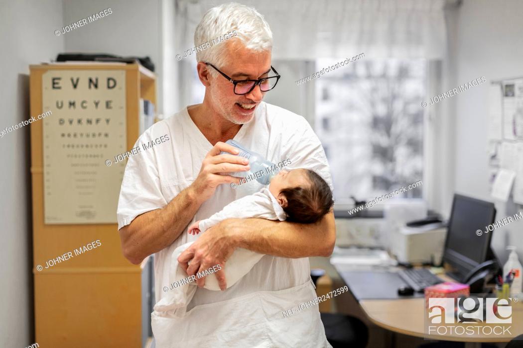 Stock Photo: Doctor feeding newborn baby.