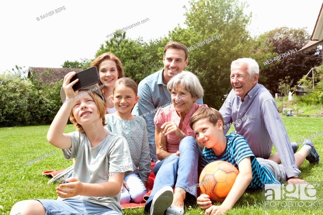 Stock Photo: Boy taking selfie of happy extended family in garden.