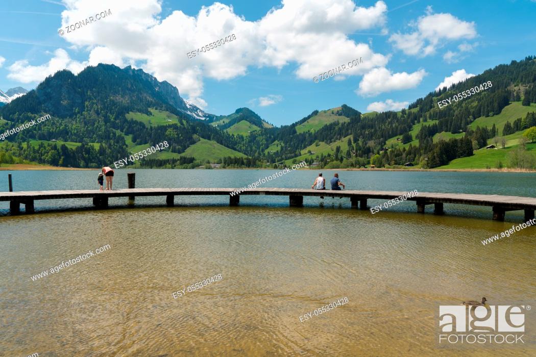 Stock Photo: Schwarzsee, FR / Switzerland - 1 June 2019: tourists enjoy the summer lakeside view at the Schwarzsee Lake in the Swiss Alps in canton Fribourg.