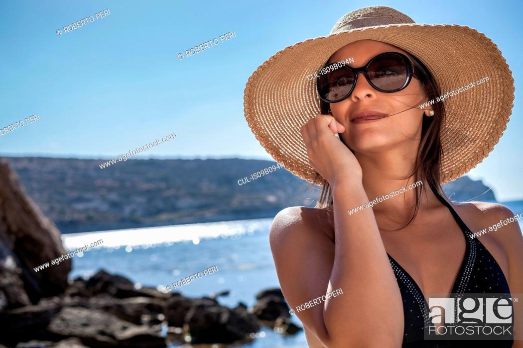 Stock Photo: Beautiful young woman wearing sunhat on beach, Villasimius, Sardinia, Italy.