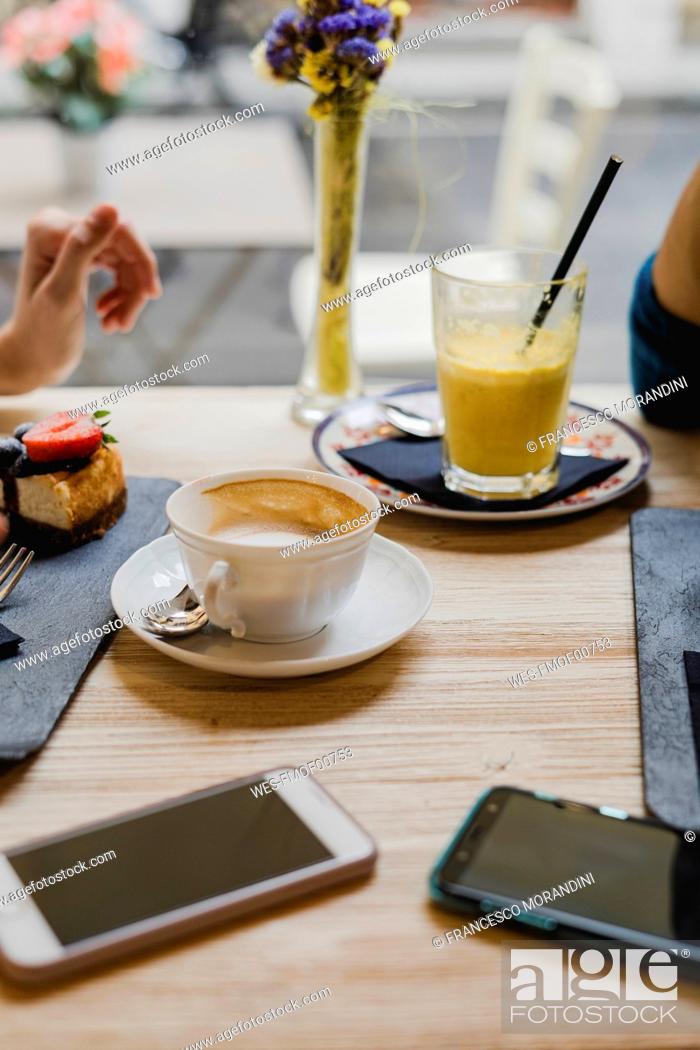 Stock Photo: Cell phones, cake and drinks on table in a cafe.