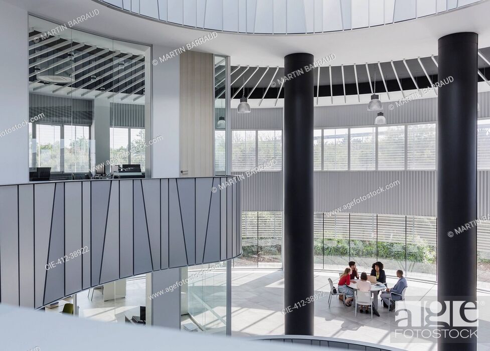 Imagen: Business people meeting at table in architectural, modern office atrium.