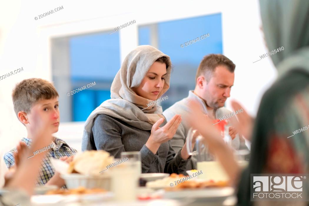 Stock Photo: modern muslim family praying before having iftar dinner together during a ramadan feast at home.