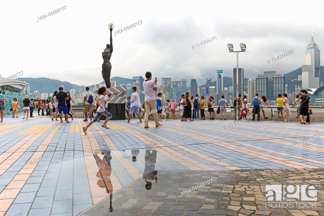 Stock Photo: Tourists walking near the bronze statue of Hong Kong Film Awards and skyline in Avenue of Stars, China.