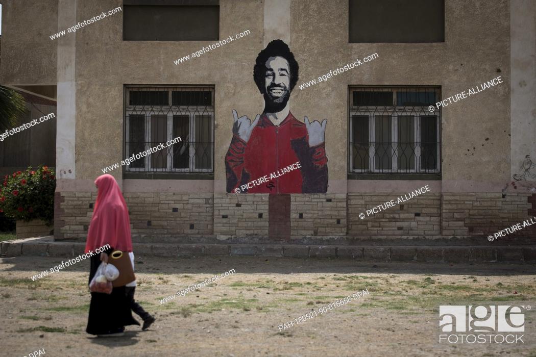 Stock Photo: dpatop - A picture made available on 21 May shows an Egyptian woman walking past a graffiti of Liverpool's Mohamed Salah.