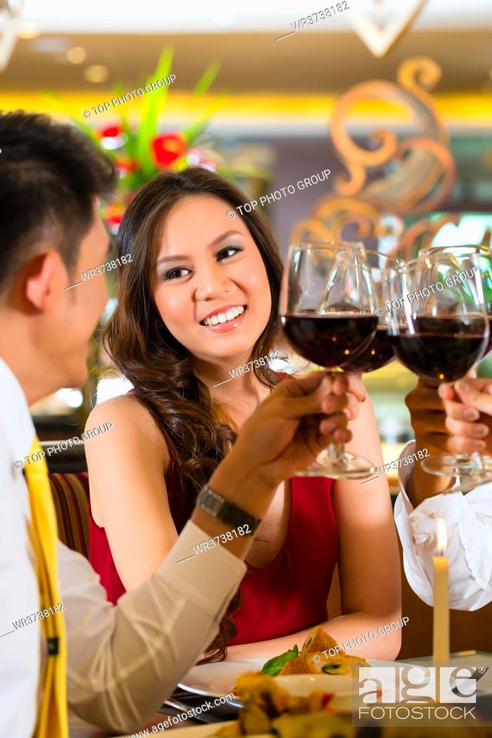 Stock Photo: Two Asian Chinese Couples or friends or business people toasting during dinner or lunch in a elegant restaurant with red wine glasses.