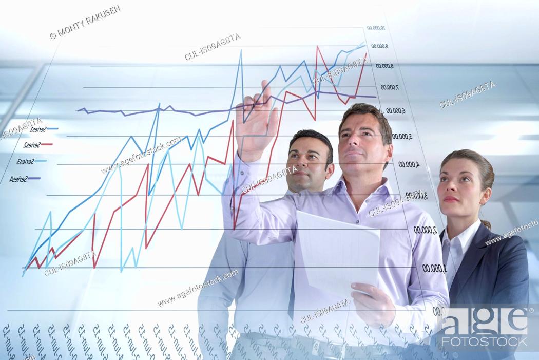 Stock Photo: Business colleagues discussing graphs and charts seen on interactive display.