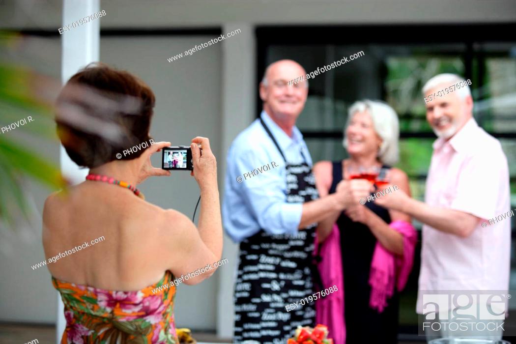 Stock Photo: Elderly woman photographing a group of senior citizens in the process of toast.