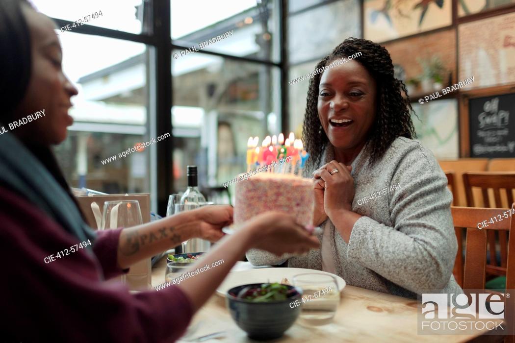 Stock Photo: Happy mother and daughter celebrating birthday with cake in cafe.