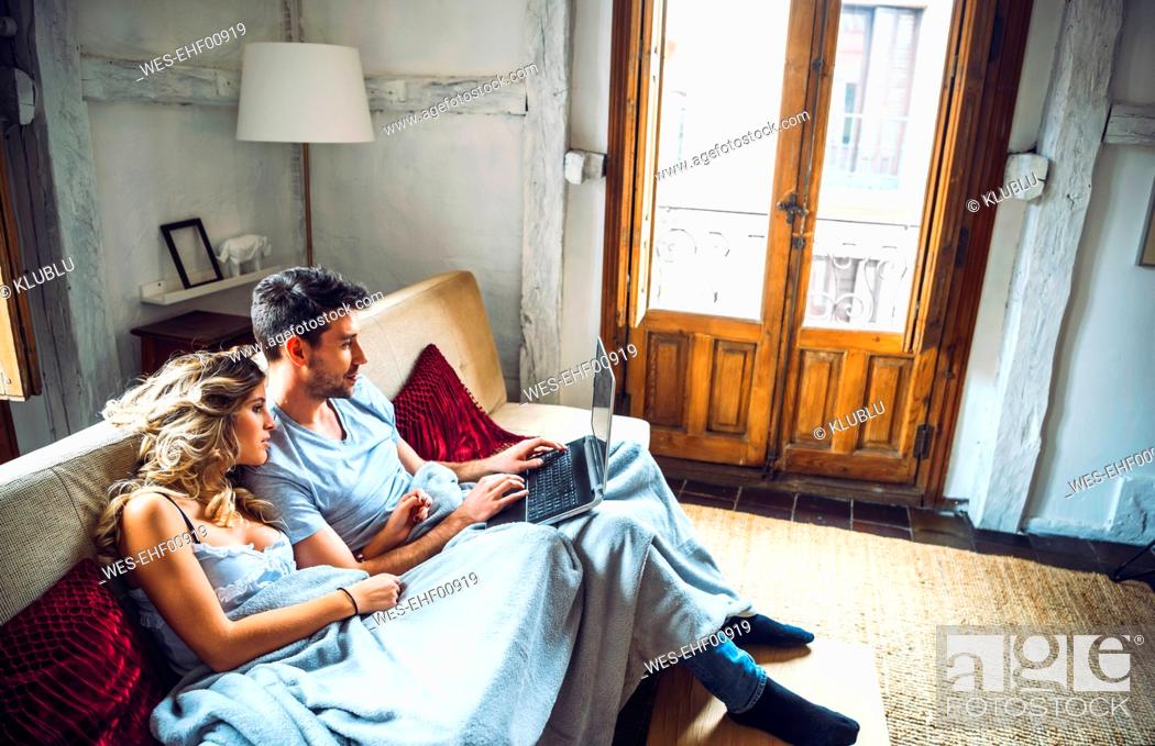 Stock Photo: Young couple sitting on couch at home watching laptop.