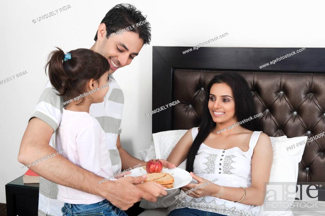 Stock Photo: Girl with her father giving breakfast to her mother.