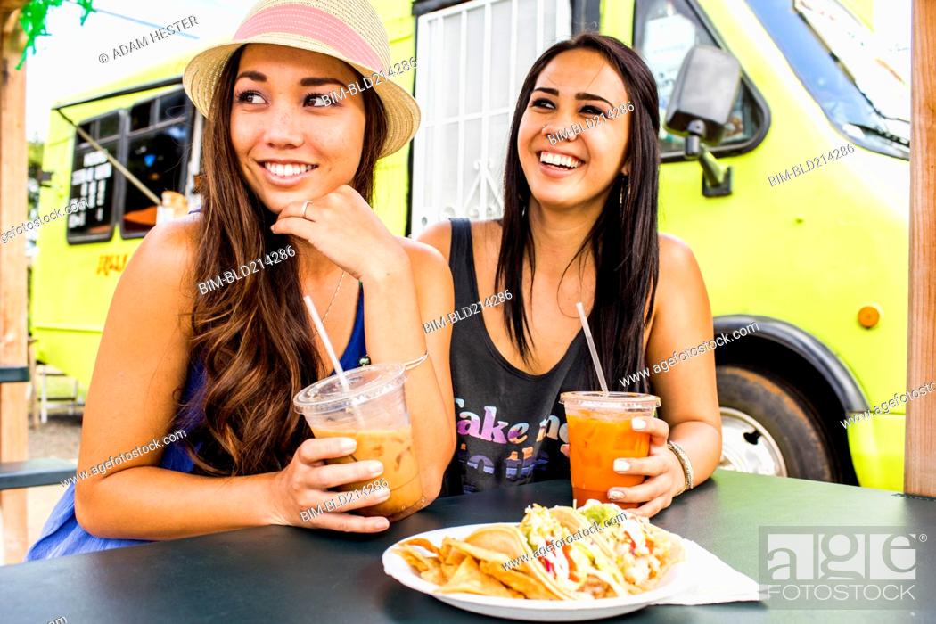 Stock Photo: Pacific Islander women eating and drinking near food cart.