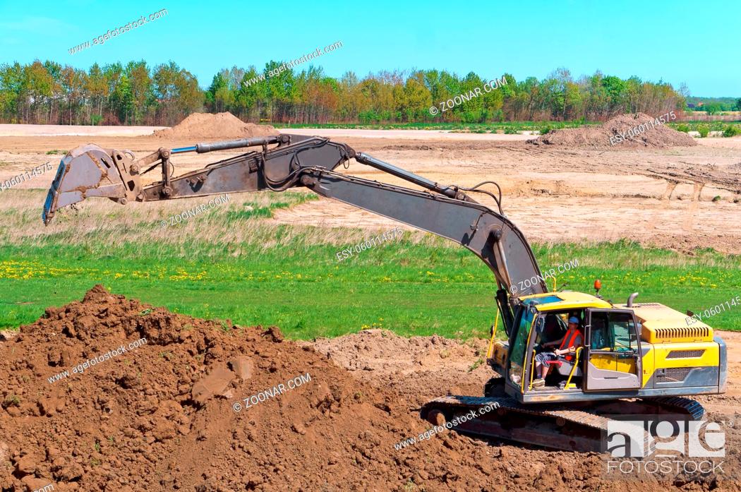 Stock Photo: the excavator digs the ground, the excavator works as a bucket, earthmoving machinery in the case.