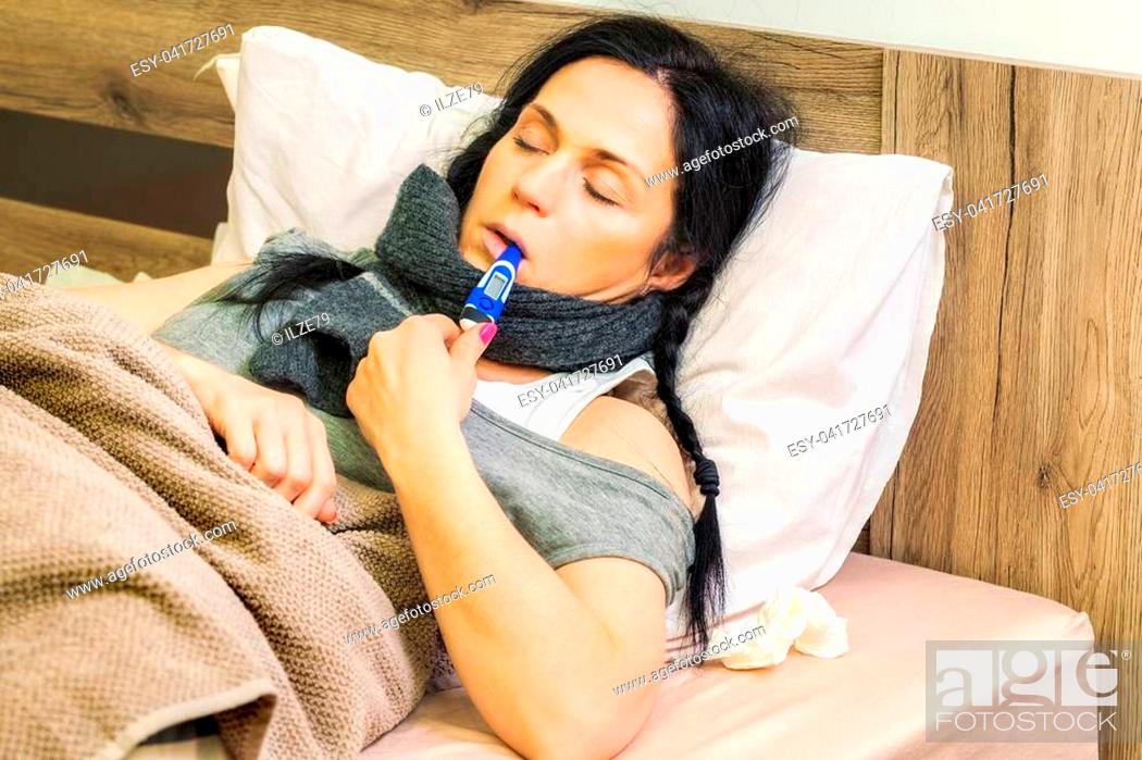Stock Photo: Sick woman keeping thermometer in mouth.