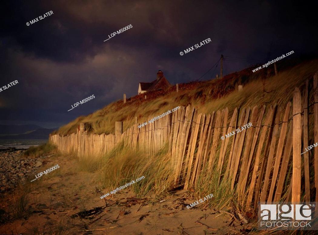 Stock Photo: Wales, Gwynedd, Harlech, Beach view of house with fence during stormy weather.