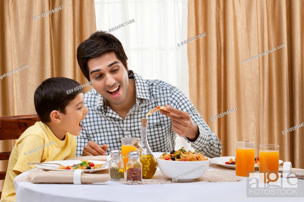 Stock Photo: Happy father and son having pizza at restaurant.