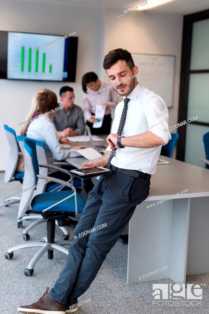 Stock Photo: Portrait of happy young businessman with tablet computer office. People group on team meeting in background.