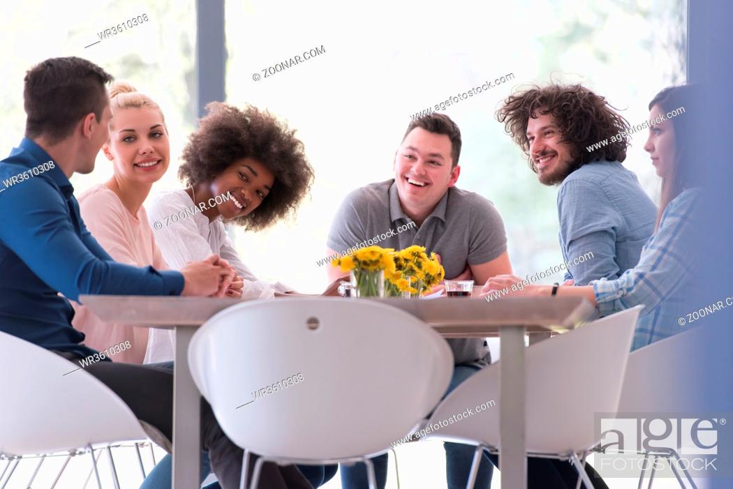 Stock Photo: Multiethnic startup business team on meeting in modern bright office interior brainstorming, working on laptop and tablet computer.