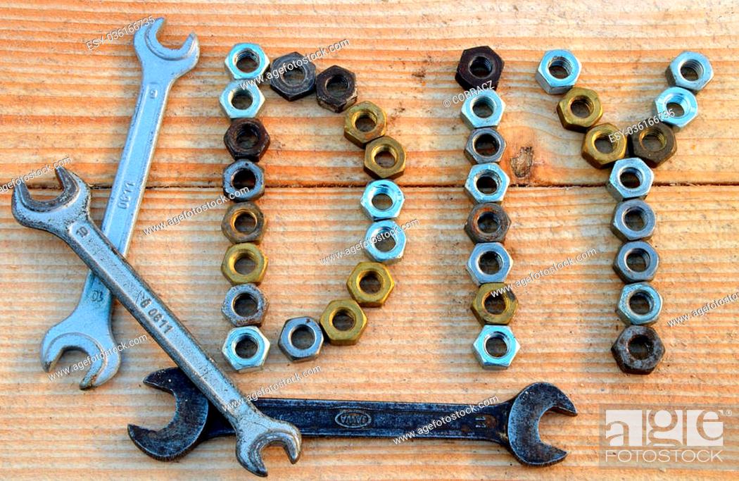 Stock Photo: DIY (do it yourself) text from small nuts and spanners on wooden desk background.