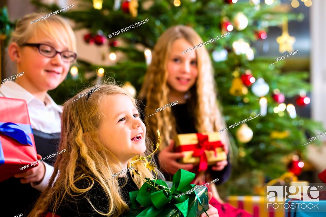 Stock Photo: Children with Christmas gift on Christmas day in family home under tree.