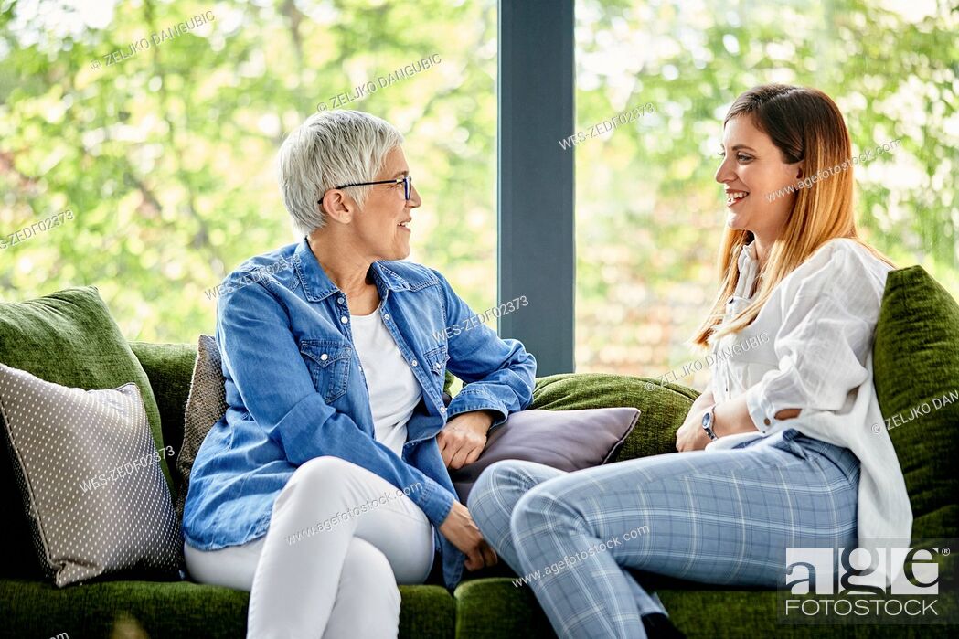 Stock Photo: Mother and adult daughter sitting on couch, talking.