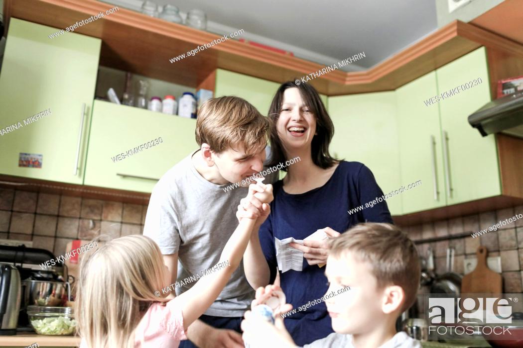 Stock Photo: Boy opening surprise egg, daughter feeding father with chocolate, mother laughing.